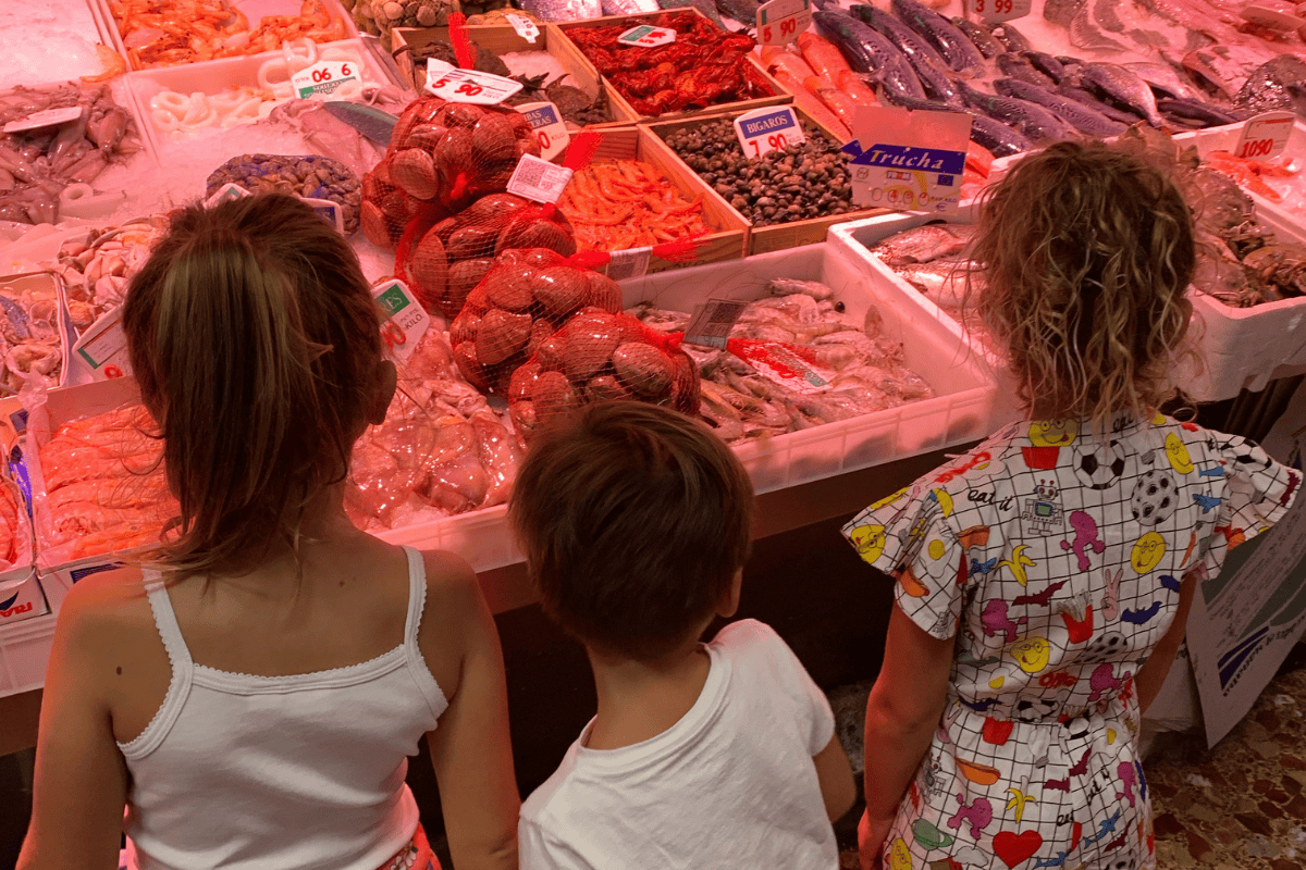 Kids on a food tour at a market, looking at seafood