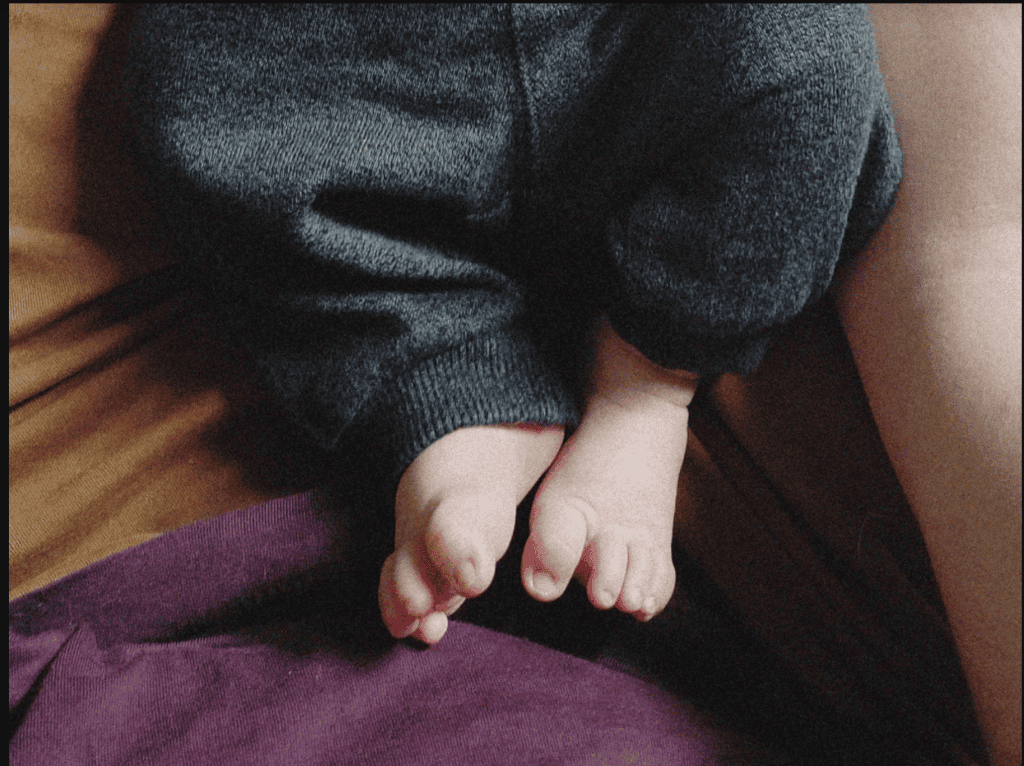 The legs of a baby in grey sweatpants
