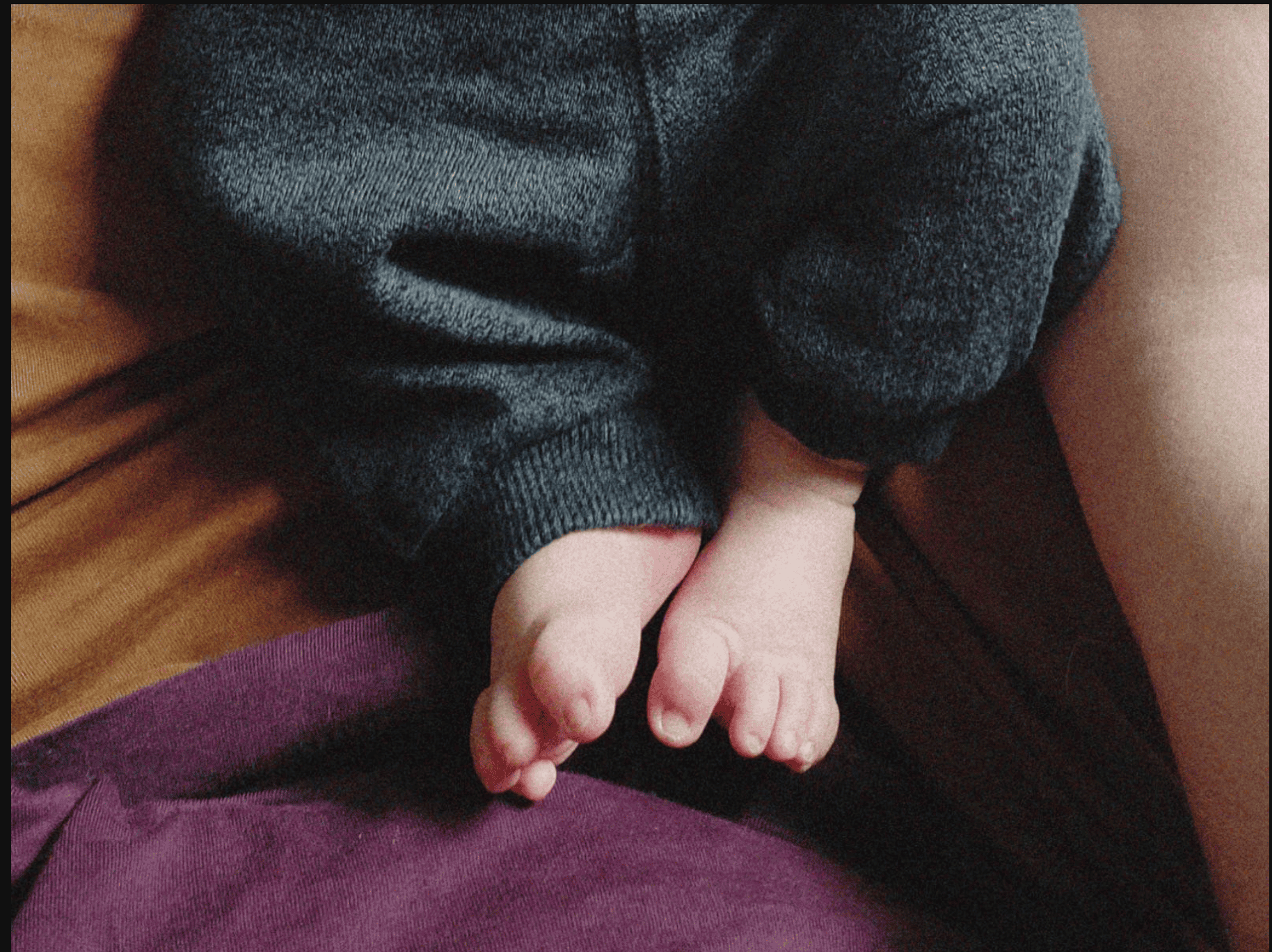 The legs of a baby in grey sweatpants