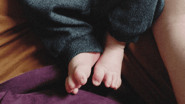 The legs of a baby in grey sweatpants